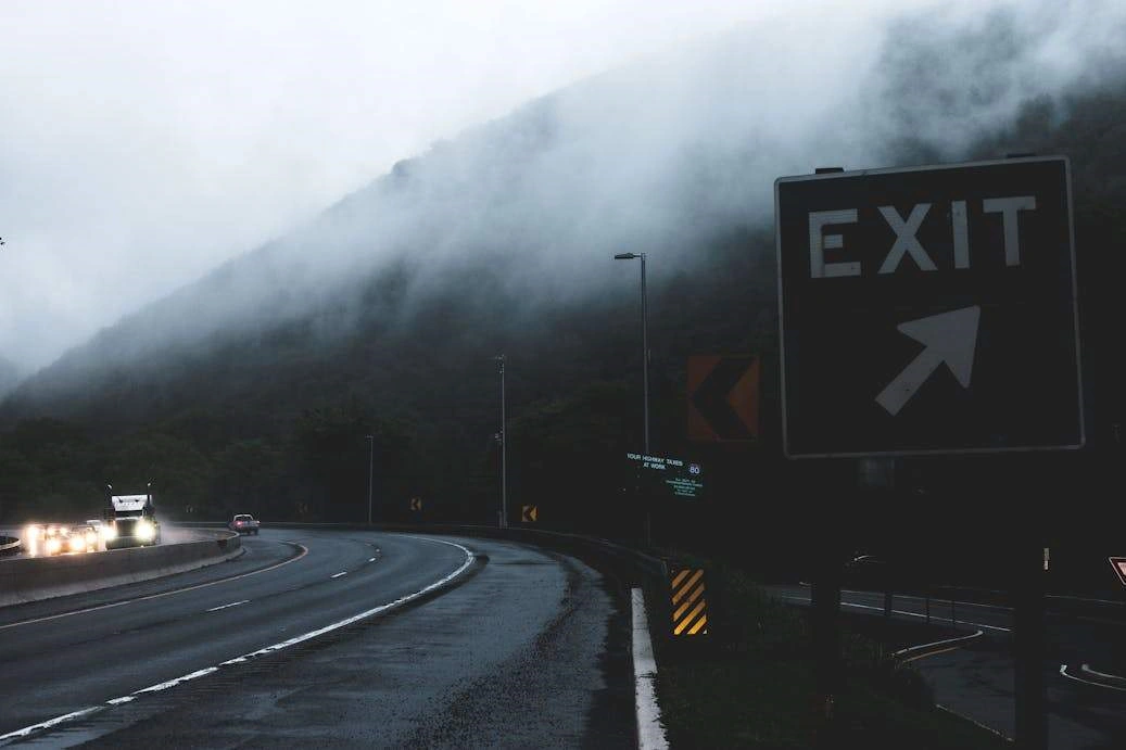Black and white exit signage on roadside.